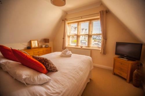 a bedroom with a bed with red pillows and a television at Hartland Heights in Woolacombe