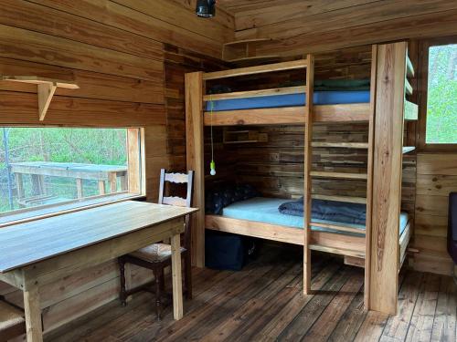 a bedroom with bunk beds and a desk in a cabin at La Cabane du Bûcheron in La Teste-de-Buch