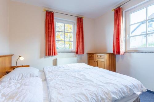 two beds in a bedroom with red curtains at Fewo Seelenanker in Thiessow