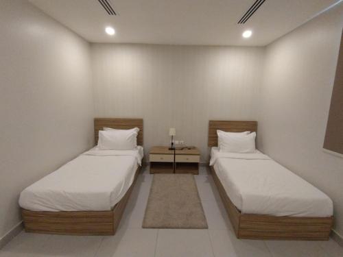 two twin beds in a room with at SPAR Serviced Apartments- سيبار للشقق المخدومة in Al Hofuf