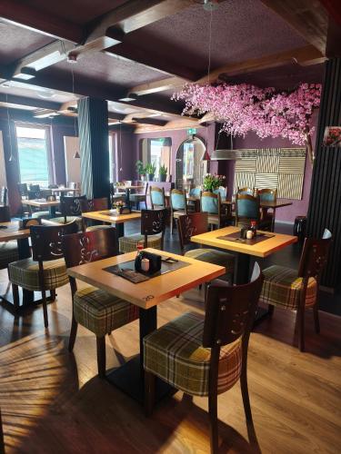 a restaurant with wooden tables and chairs and pink flowers at Vinami Hotel - Bad Wildbad in Bad Wildbad