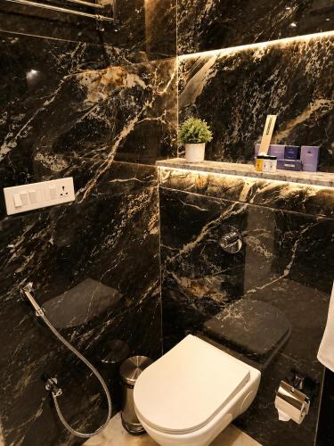 a bathroom with a toilet and a black marble wall at Solenne Retreat in Bodh Gaya