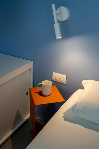 a orange table with a cup on it next to a bed at VIVO Rooms in Civitanova Marche