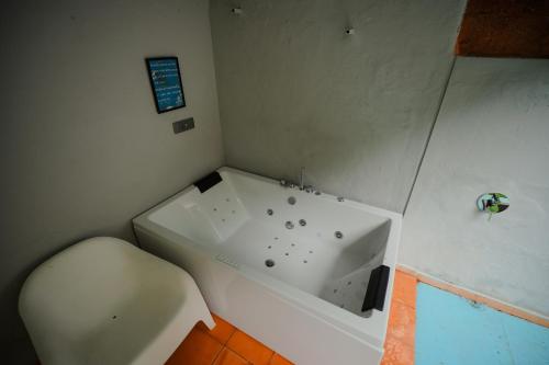 a bathroom with a white tub and a toilet at Red Earth Kabini in Begūr