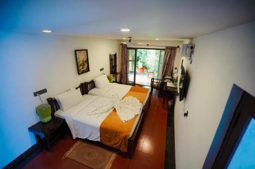 a bedroom with a bed and a desk and a window at Red Earth Kabini in Begūr