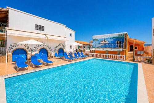 a swimming pool with blue chairs and a building at Kavos Panorama Hotel in Kavos