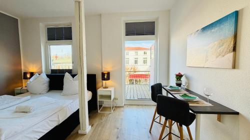 a bedroom with a bed and a table and a desk at CBlue "Admiralsloge - Nauticus" in Warnemünde