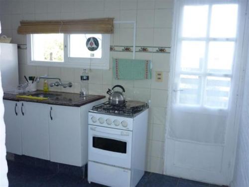 a white kitchen with a stove and a sink at Kactus- Balneario Buenos Aires in Balneario Buenos Aires