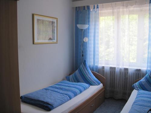 Schlafzimmer mit einem Bett mit blauer Bettwäsche und einem Fenster in der Unterkunft Ferienwohnung Nähe Stadtzentrum in Saarbrücken