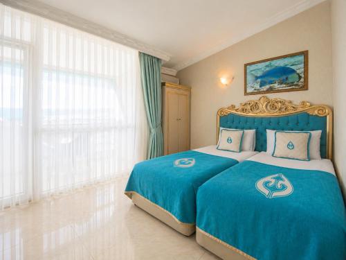 a hotel room with a bed with a blue bedspread at Daima Biz Hotel - Dolusu Aquapark Access in Kemer