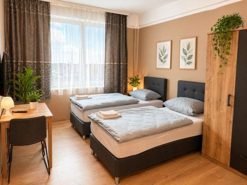 a bedroom with two beds and a table and a desk at Pension Sara in Magdeburg