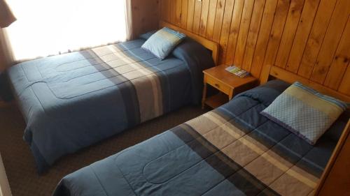 a bedroom with two beds and a night stand with a bedphasis at Hostal Costa Azul in Castro