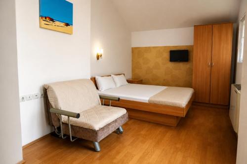 a small bedroom with a bed and a chair at Livija rooms in Petrovec