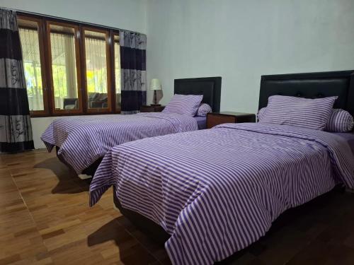 two beds in a room with purple and white sheets at Rumah Pantai Patang in Jati