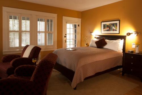 a bedroom with a bed and two chairs at Showers Inn in Bloomington