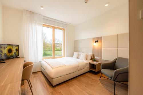 a bedroom with a bed and a chair and a window at Cessange House by Rentaroo in Luxembourg
