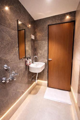 a bathroom with a sink and a wooden door at Ruby Hotel in Mumbai