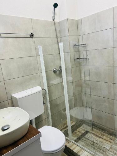 a bathroom with a toilet and a glass shower at Casa Bradu in Mangalia