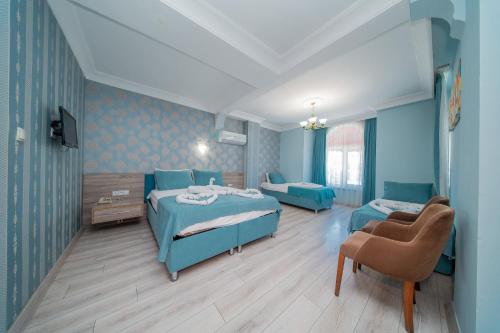 a blue room with two beds and a chair at Sava Hotel in Antalya