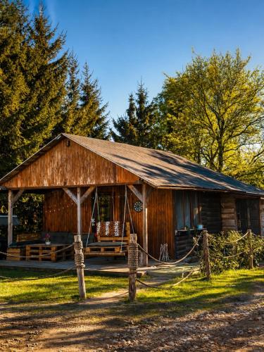 a wooden barn with a fence in front of it at Domki Na Ranczo in Gniezno