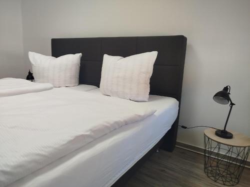 a bed with white pillows and a black headboard at Ferienwohnung Friederike Luise in Bad Freienwalde