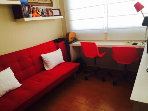 a living room with a red couch and two red chairs at Casa Paraiso in Caleta De Fuste