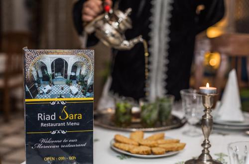 a table with a plate of crackers and a bottle of red saar wine at Riad Sara in Fès