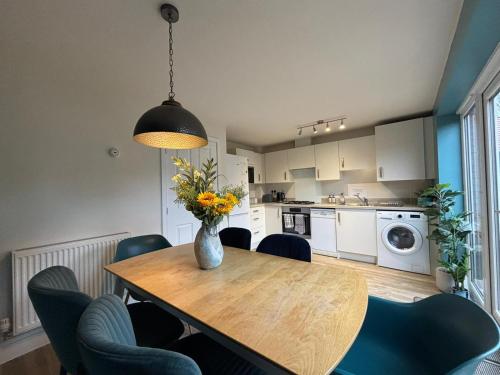 a kitchen with a table with chairs and a vase with flowers at 3 Beds with off-street parking for 2 cars, fast Wifi, sleeps 6 in Ashby de la Zouch