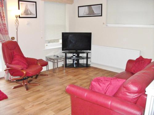 a living room with a red couch and a flat screen tv at Watch House in Fowey