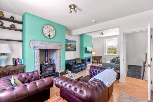 a living room with leather furniture and a fireplace at John Brown Cottage in Skipton