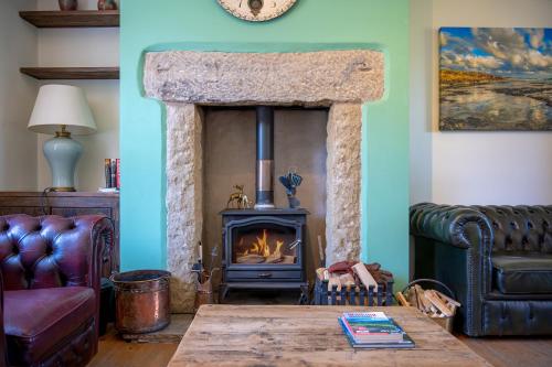 a living room with a stone fireplace and a table at John Brown Cottage in Skipton