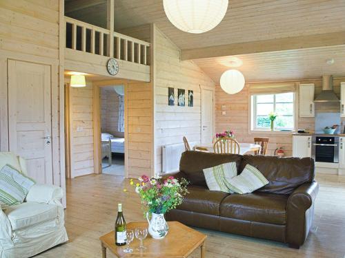 a living room with a leather couch and a table at Skylark Lodge - Uk51678 in Carsethorn