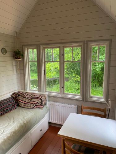 a room with a bed and a table and windows at Fint Tiny house på Österlen in Sankt Olof