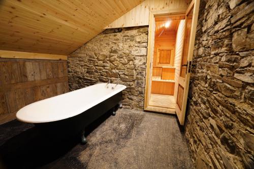 a bathroom with a bath tub in a stone wall at Rockfield House in Kells