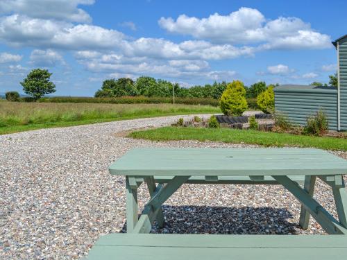 a green picnic table sitting on a gravel road at Sycamore - Uk47621 in Hunmanby