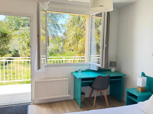a bedroom with a blue desk and a window at Logis Hôtel La Demeure du Perron in Quettehou