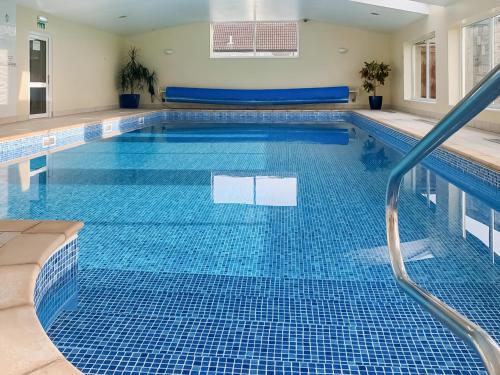a swimming pool with a blue tiled floor and a swimming pooliterator at The Wrens - Uk50181 in Mare Green