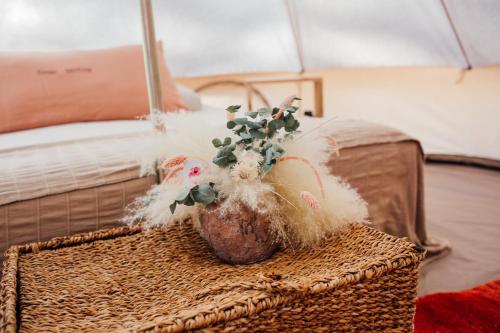 a vase with a plant in it sitting on a bed at The Glamping Spot - Douarnenez in Plonévez-Porzay