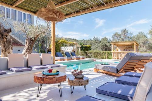 a patio with lounge chairs and a swimming pool at Artemis' Garden in Skopelos Town