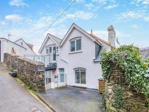 a white house with a stone wall at Gwendrock Diw in Looe