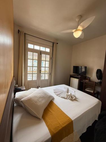 a bedroom with a large white bed with a window at Pousada Contos de Minas in Mariana