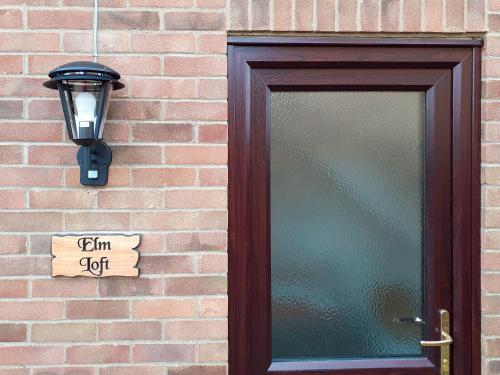 a door with a light and a sign on a brick wall at Elm Loft in Upton