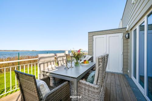a table and chairs on a balcony with the ocean at Ferienhaus Hamptons Beach House Olpenitz in Olpenitz