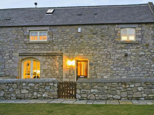 a stone house with a stone fence in front of it at Murton Cottage in East Ord