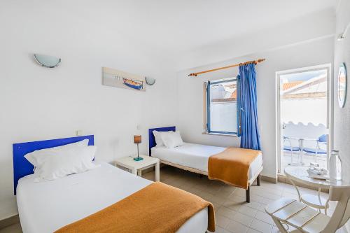 a bedroom with two beds and a table and a window at HI Lagos - Pousada de Juventude in Lagos