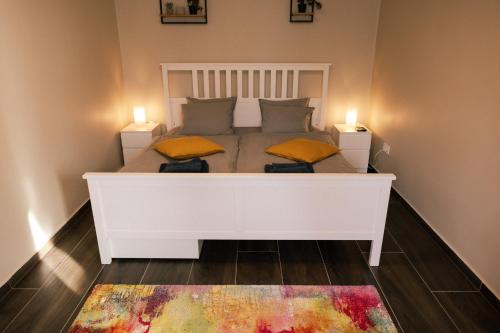 a white bed in a room with two candles on it at Dunavirág Vendégház in Pilismarót