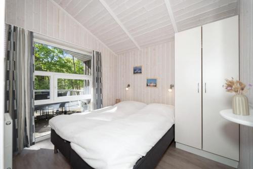a bedroom with a large white bed and a window at Schmugglerstieg - Dorf Ferienhaus 03 in Priwall