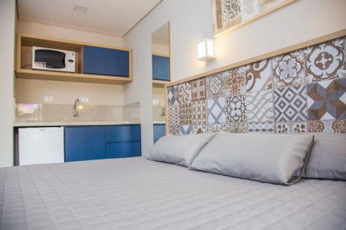 a bedroom with a large bed and a kitchen at Spazio Marine Hotel - Guaratuba in Guaratuba
