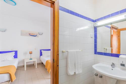 a bathroom with a bed and a sink and a mirror at HI Lagos - Pousada de Juventude in Lagos