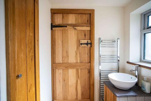 a bathroom with a wooden door and a sink at March Hare Cottage in Bretforton in Bretforton